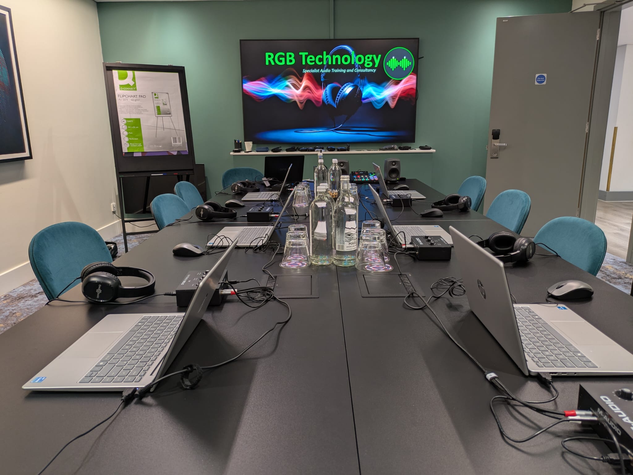 RGB Technology training room set up for practical audio training, with laptops, headsets and audio equipment around a conference table.